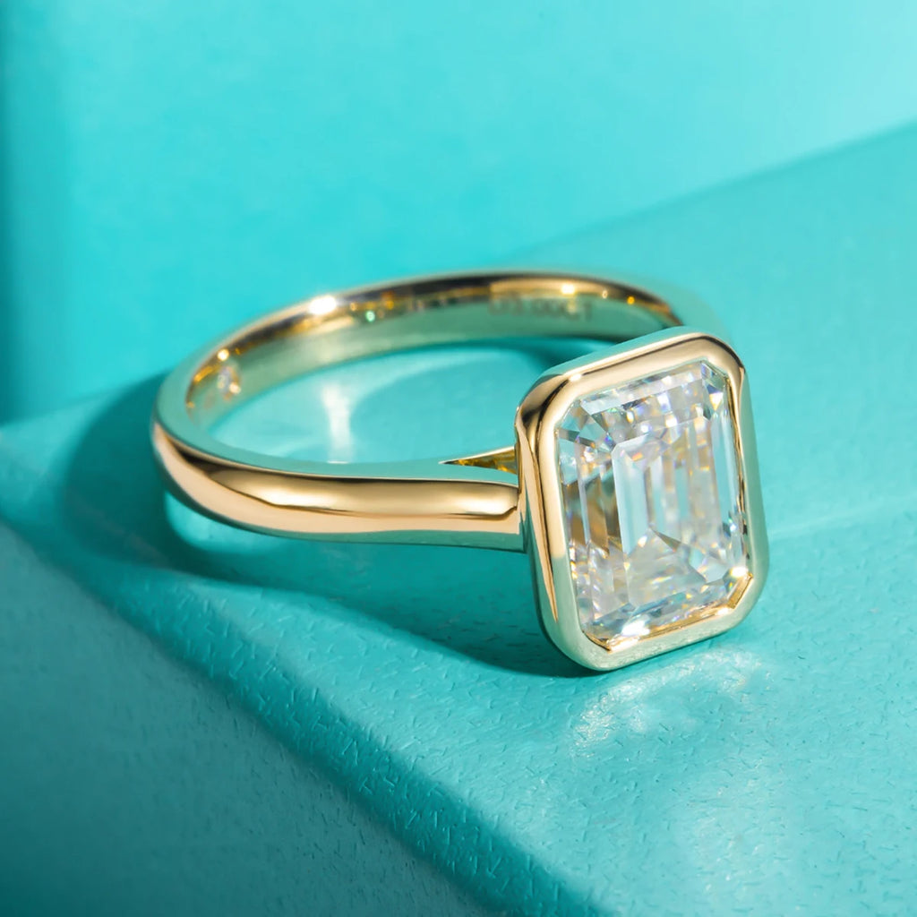Emerald cut moissanite 3ct D color VVS1, yellow gold bezel setting detail — Aurora Moissanite